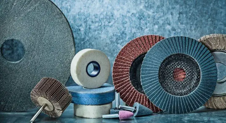 Multiple abrasive tools of various colors and sizes sit on a blue marble table in front of a blue and gray background.