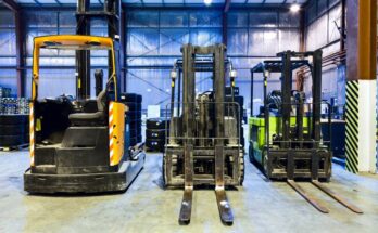 A row of forklifts sitting in a warehouse, each using a variety of power sources from electric to propane.