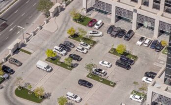 An aerial shot of an incredibly clean commercial parking lot shows many cars parked in various parking spots.