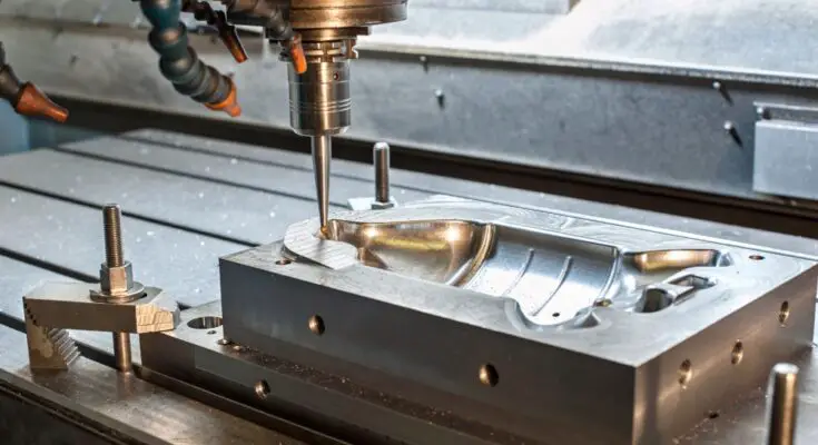 Industrial machine with tubes and a large mill manufacturing a metal mold on top of an industrial table with safety locks.