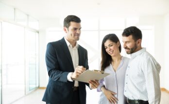 A real estate broker showing a young couple the final rental agreement of their new luxury apartment.