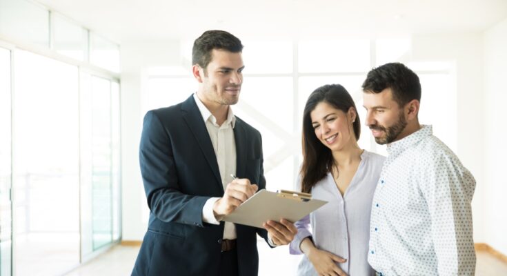 A real estate broker showing a young couple the final rental agreement of their new luxury apartment.