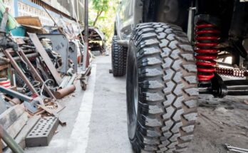 A close-up of the front wheel and suspension system on the passenger side of a four-wheel drive pickup truck.