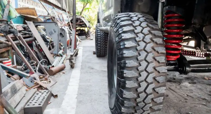 A close-up of the front wheel and suspension system on the passenger side of a four-wheel drive pickup truck.