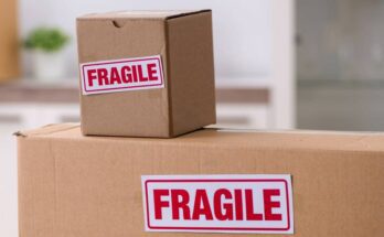 Three cardboard boxes stacked on top of each other. Two of the boxes have white stickers that say "fragile" in red letters.