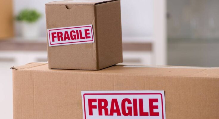 Three cardboard boxes stacked on top of each other. Two of the boxes have white stickers that say "fragile" in red letters.