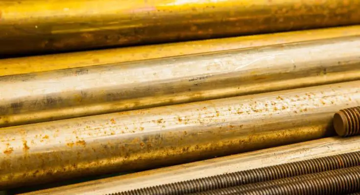 Large bronze round bars and steel threaded rods neatly on a shelf, highlighting their metallic sheen and varying textures.