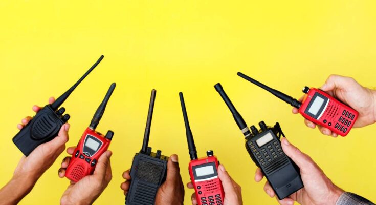 Six hands holding up red and black two-way radios in an alternating color pattern in front of a yellow background.