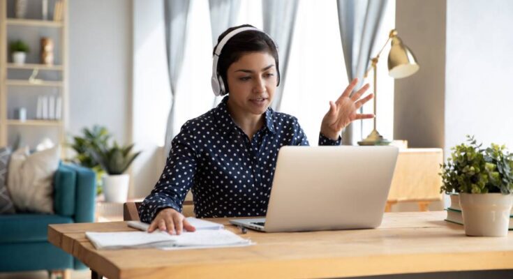 A remote worker sits at their desk in a beautifully decorated home office while hosting a virtual meeting.