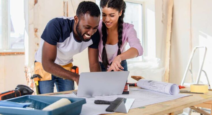 Two young homeowners preparing for home renovations by exploring different design plans on their shared laptop.