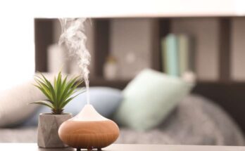 An aromatic diffuser resting on a bedroom nightstand and dispensing a thick cloud of essential oil fragrances.