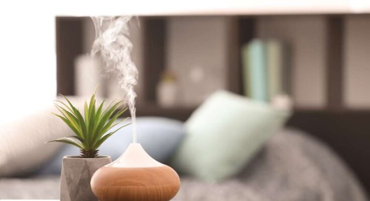 An aromatic diffuser resting on a bedroom nightstand and dispensing a thick cloud of essential oil fragrances.