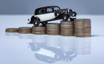 A black-and-white classic car stands on top of a stack of coins, and its reflection appears underneath the table.