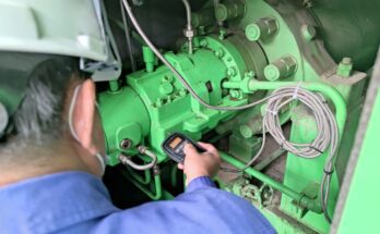 A professional technician performing vibration analysis on a piece of heavy industrial equipment to monitor its performance.