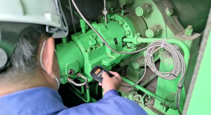 A professional technician performing vibration analysis on a piece of heavy industrial equipment to monitor its performance.