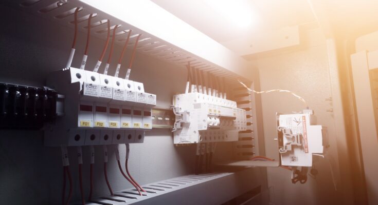 A view inside an electrical breaker with a row of switches connected to red wires that run vertically.