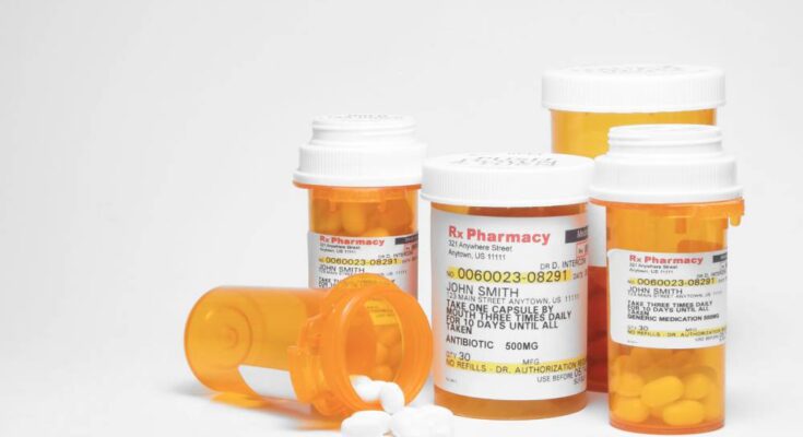 Several orange plastic medicine bottles filled with prescription pills. One bottle is turned on its side.