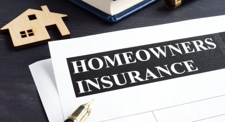 A paper document with a header reading “HOMEOWNERS INSURANCE” on a desk near an uncapped pen.