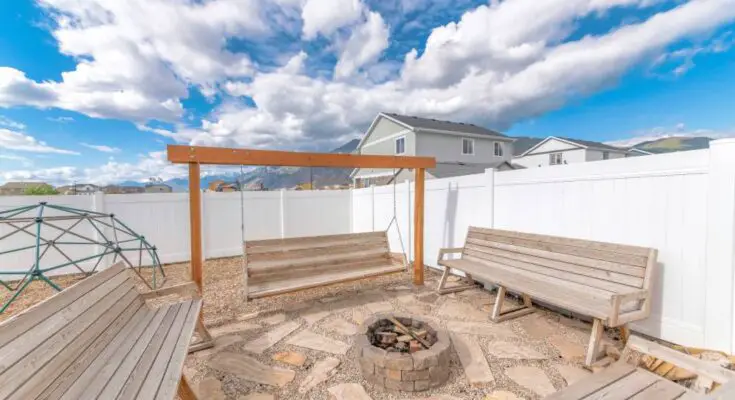 A small firepit surrounded by stone slabs and wooden benches. One of the benches is actually a swing.