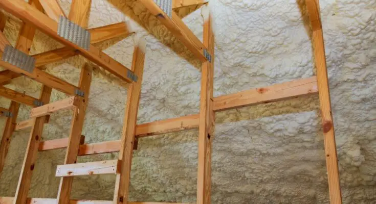 The interior of a building with bare wooden studs that have spray foam insulation between and behind them.