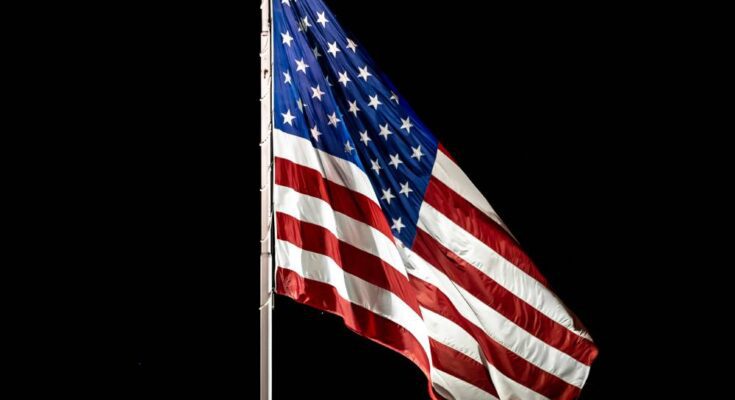 A tall flagpole proudly displaying a beautifully lit up American flag, soaring high in the night sky.