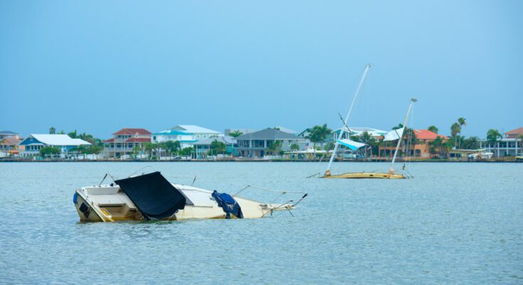 A boat going under water in the marina. There is a second boat behind it also going under the water.