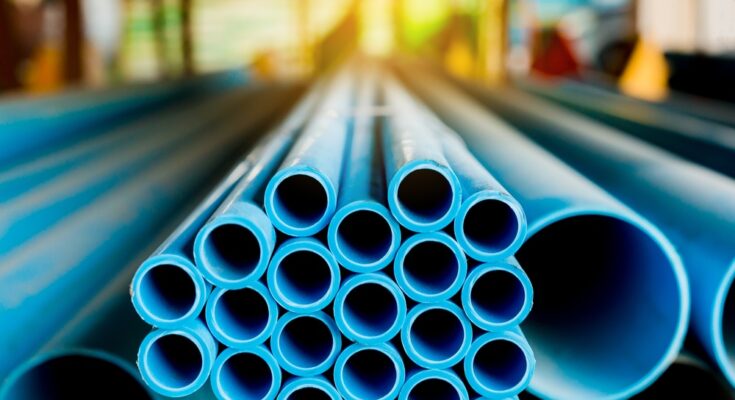 A stack of long blue plastic pipes in a warehouse. Only the mouths of the pipes are in focus.